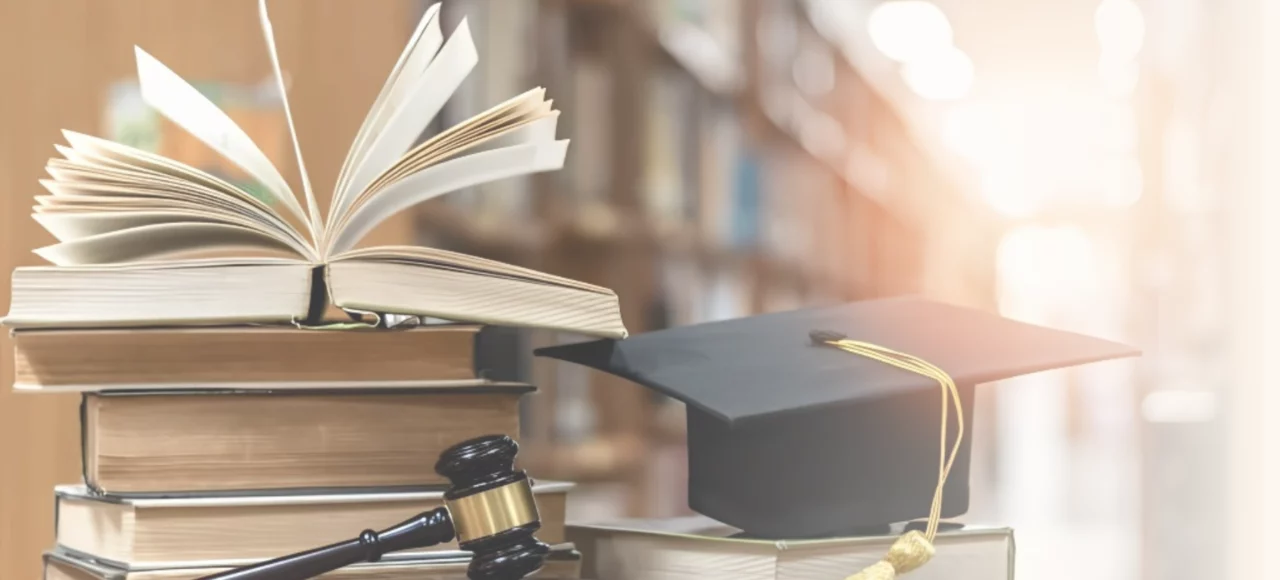 Livres juridiques, toque universitaire et marteau de juge illustrant le parcours universitaire et la formation juridique de Maître Marie Denimal